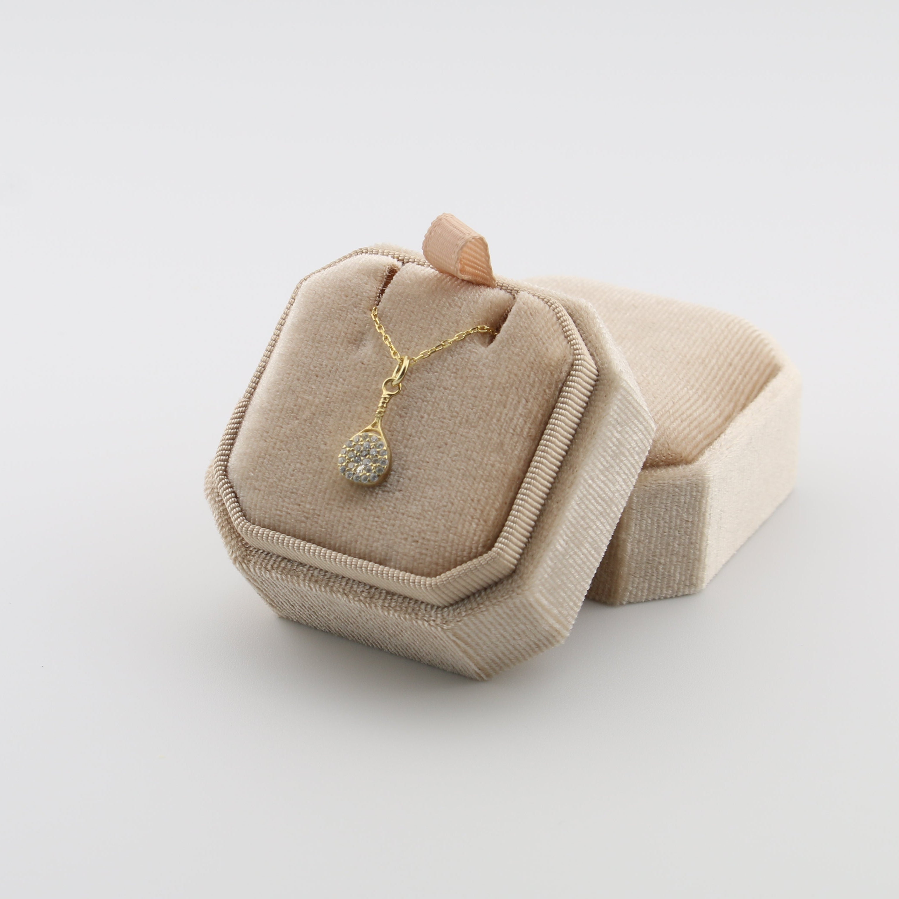 Rhinestone padel necklace with a pendant on a beige jewelry display box against a light gray background