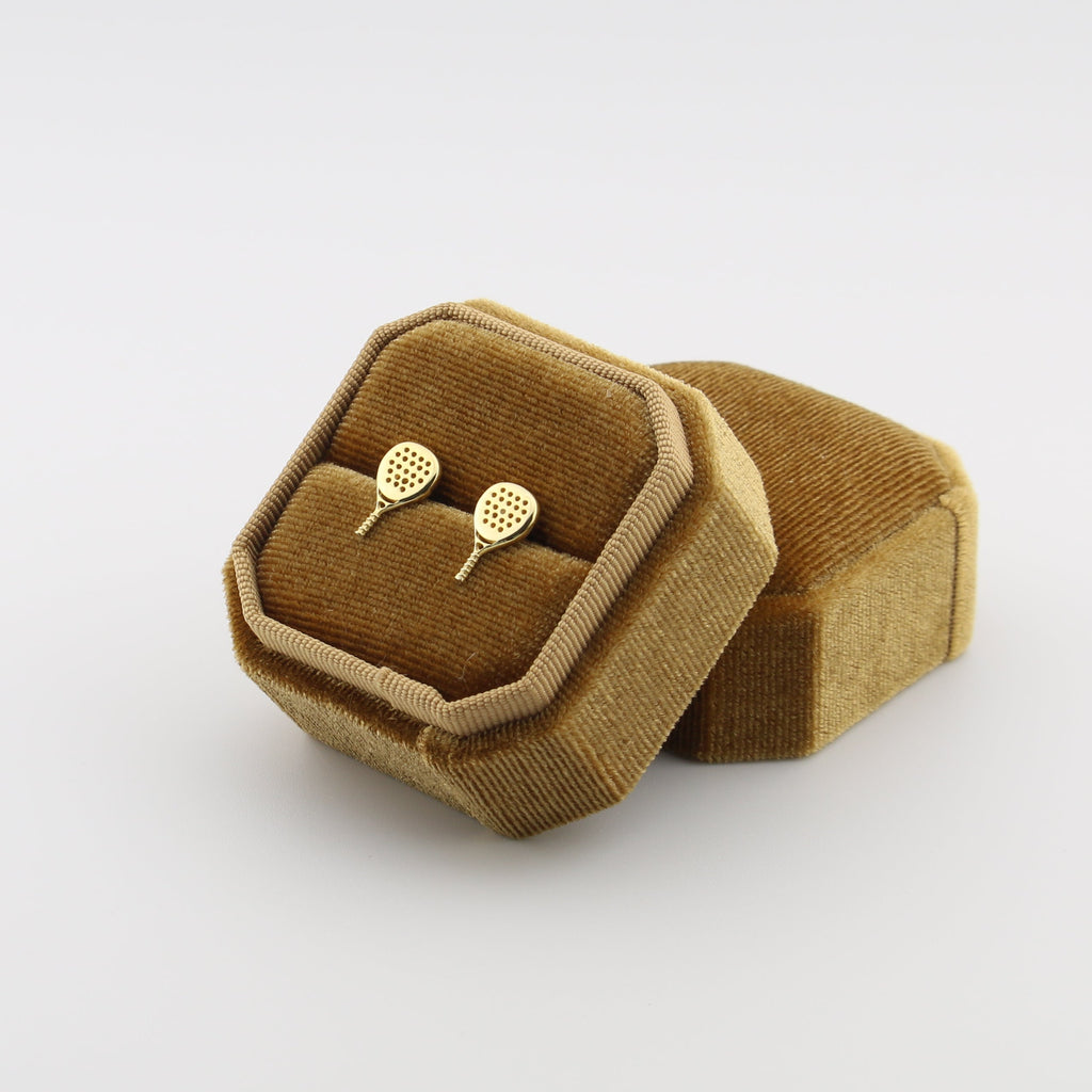 Gold padel stud earrings in a brown velvet jewelry box on a white background