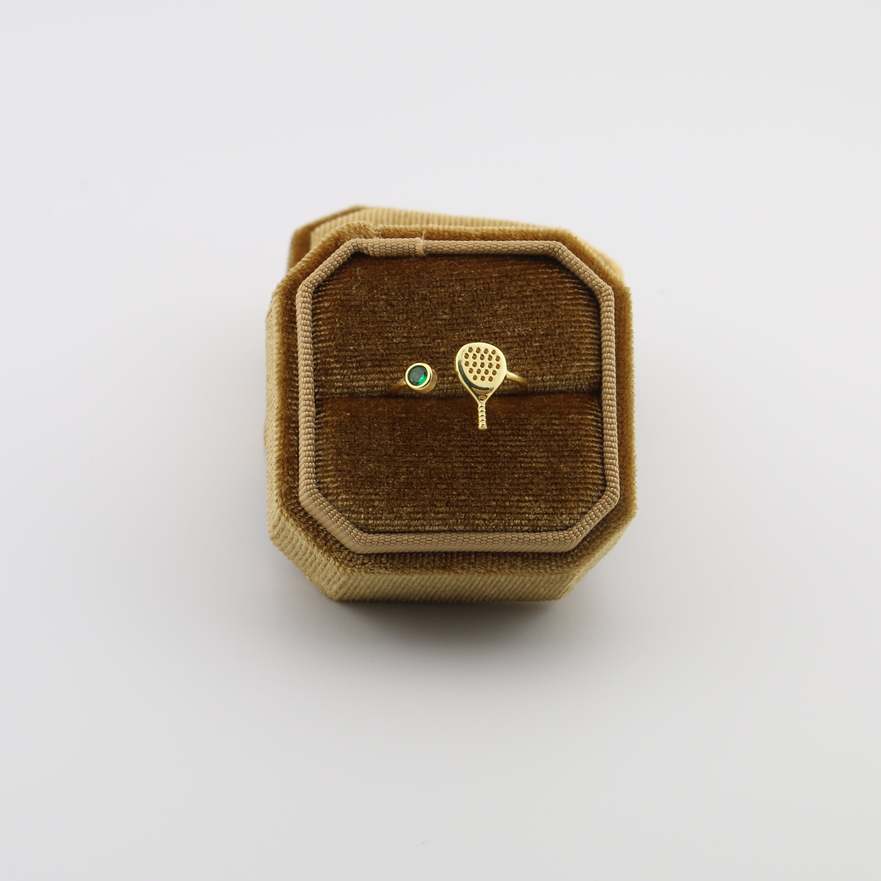 Gold padel  racket and ball brooch on a brown velvet cushion in a decorative box.