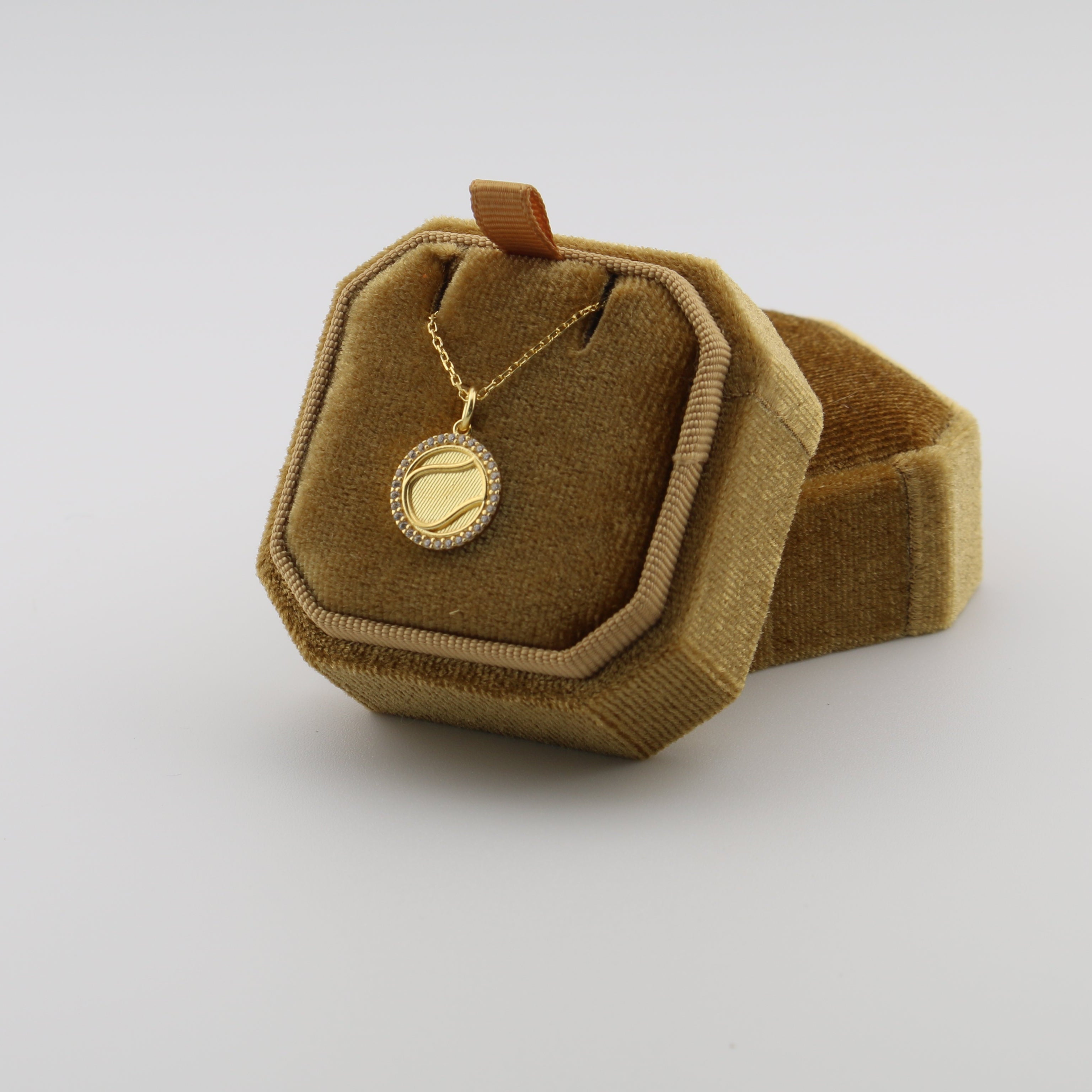 Brown velvet jewelry box with a gold necklace on a white background