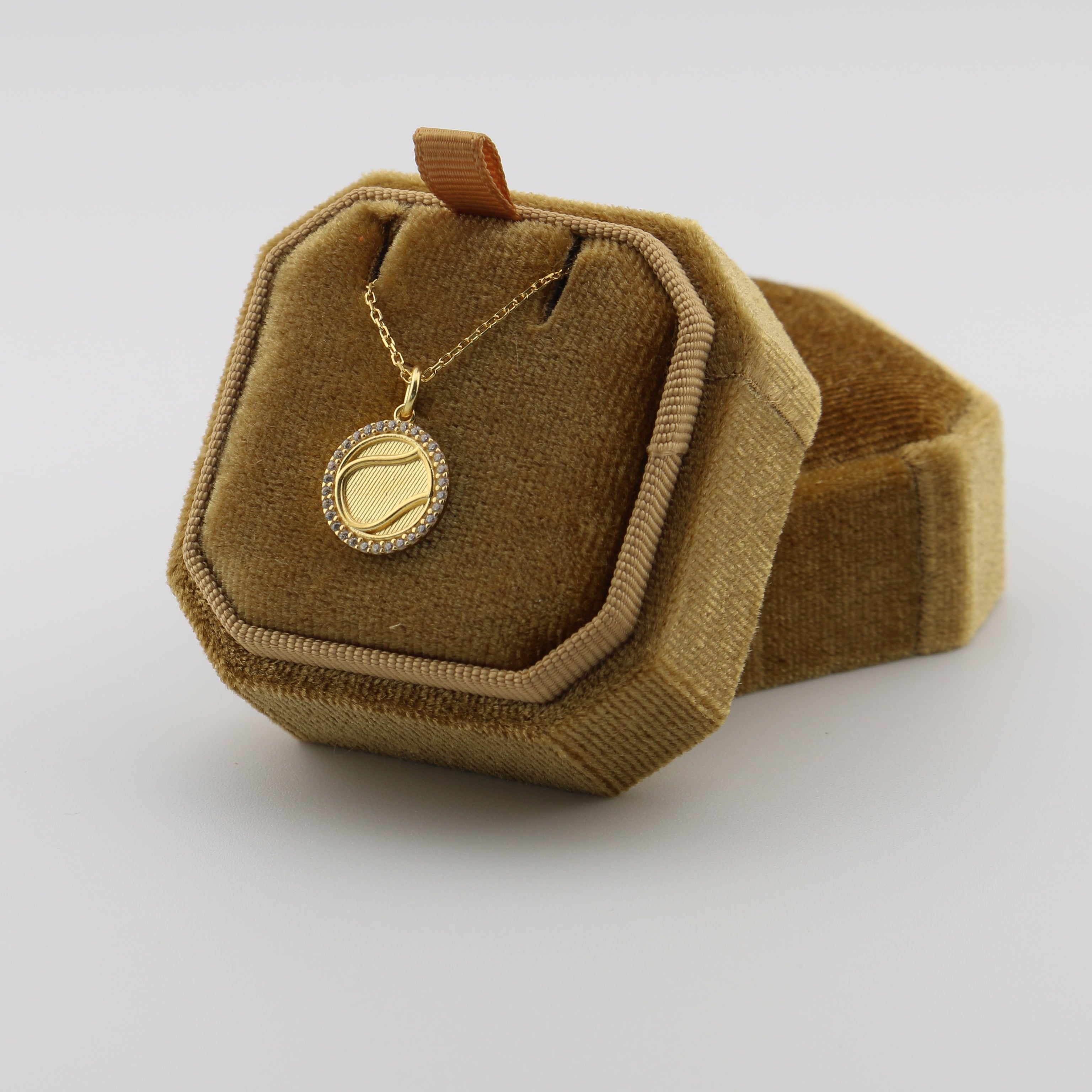 Gold necklace in a brown velvet box on a white background