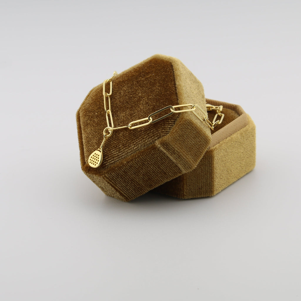 Gold necklace in a brown jewelry box on a light gray background