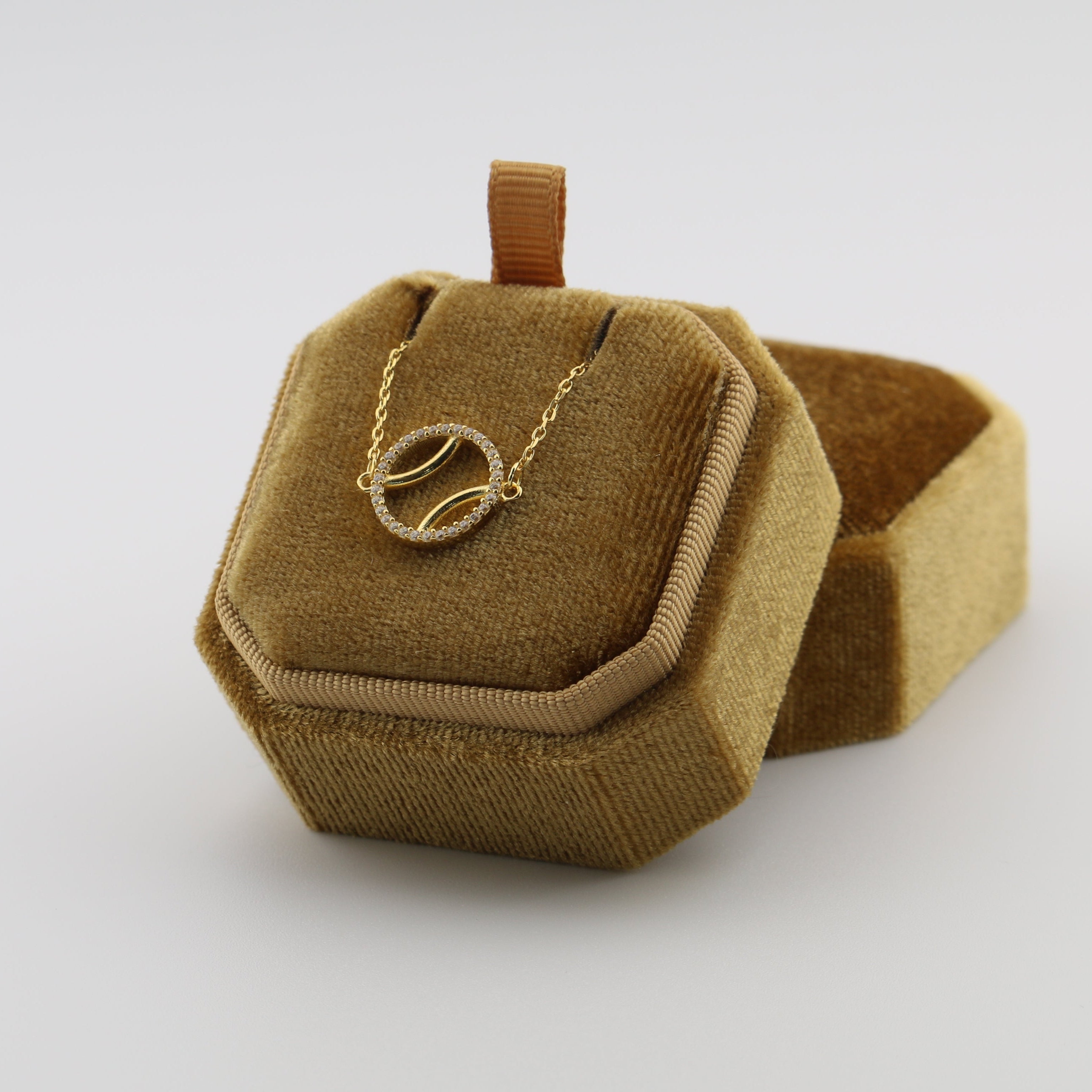 Gold necklace in a hexagonal brown velvet jewelry box on a white background