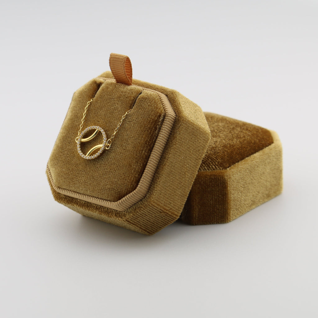 Small brown textured bag with a gold padel ball on a white background