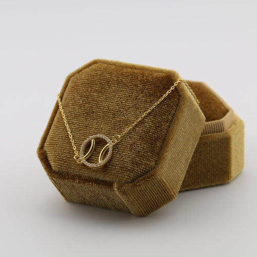 Brown geometric jewelry box with a padel ball necklace on a white background