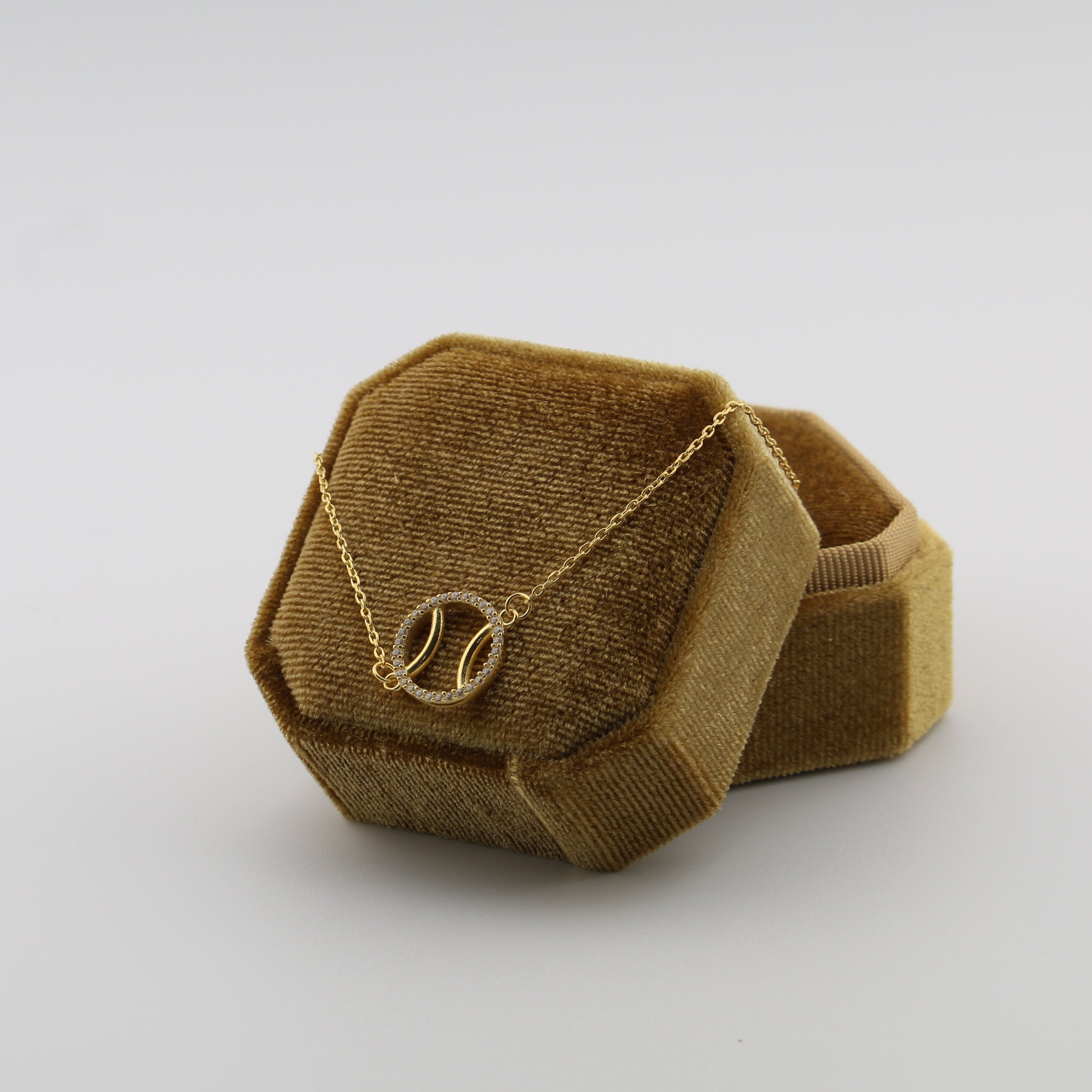 Brown hexagonal jewelry box with a padel ball necklace on a white background