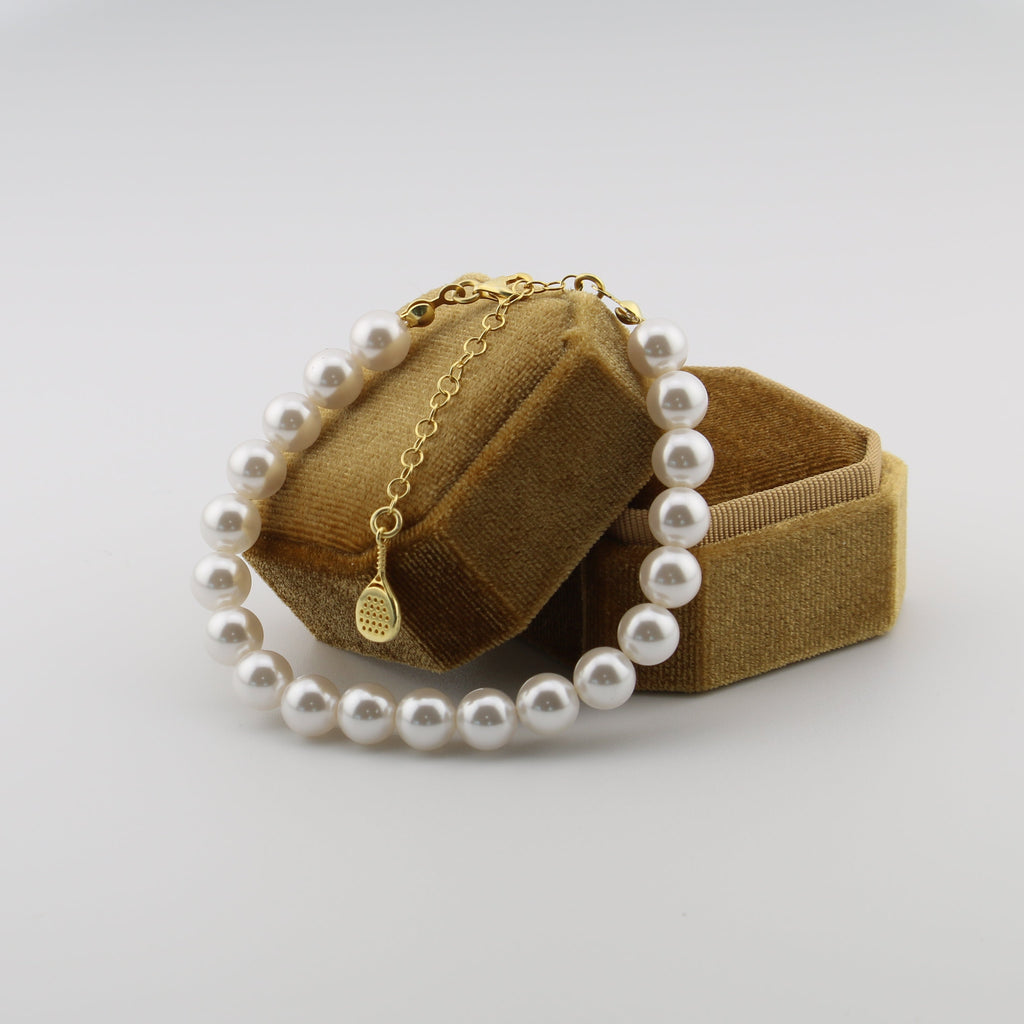 Pearl necklace with gold chain on a brown jewelry box against a white background