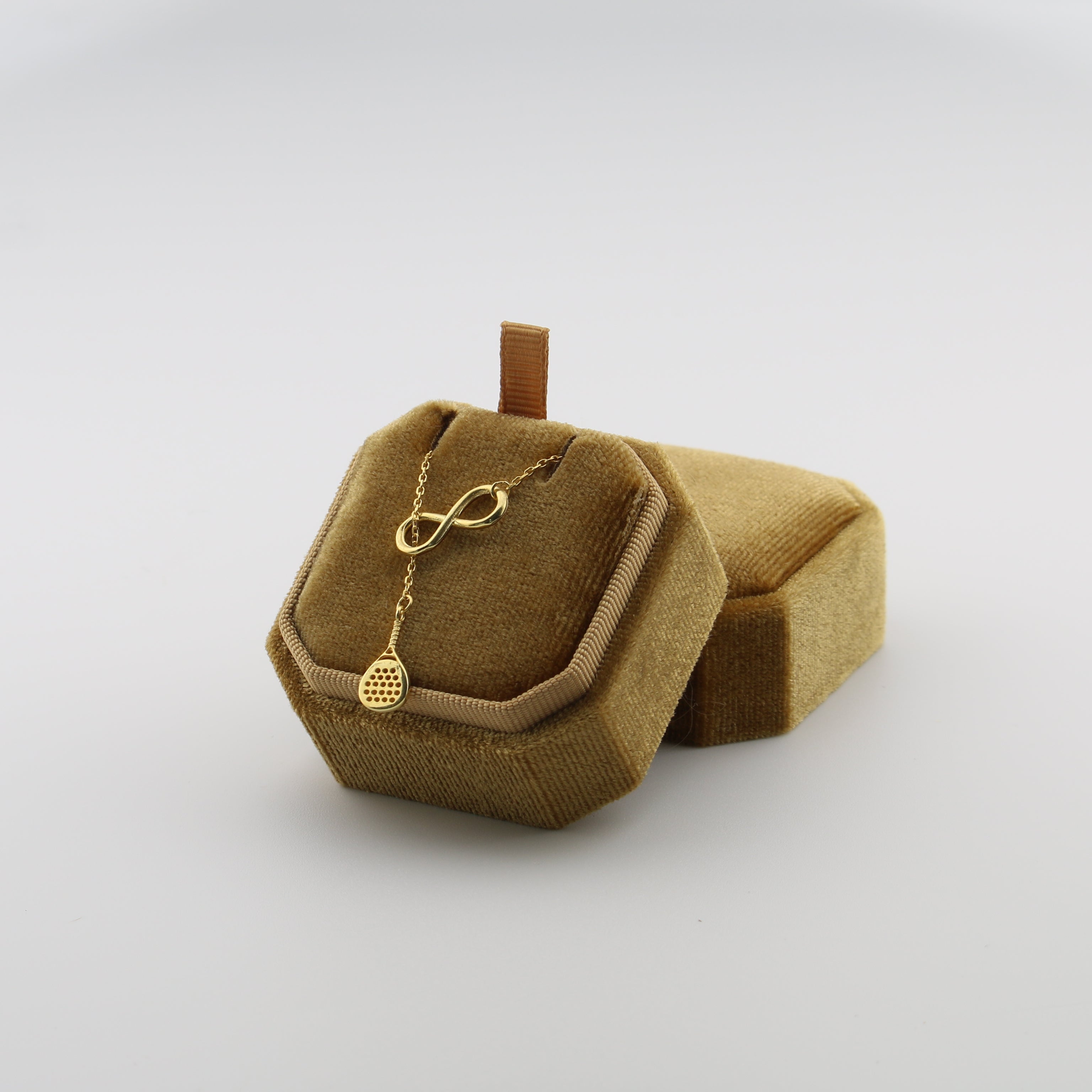Gold necklace with an infinity symbol in a brown jewelry box on a white background